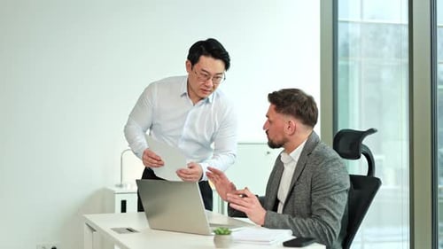 Businessmen Discussing Paperwork in a Modern Office