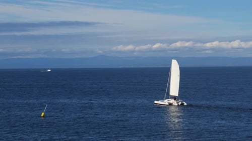 Sailboat sails smoothly across blue monterey bay California waters by drone