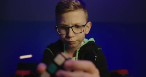 Blond Boy Solving Rubik's Cube in Blue Room