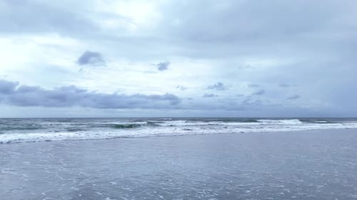 Empty Sandy Shoreline with Ocean Waves and Cloudy Sky Drone Video