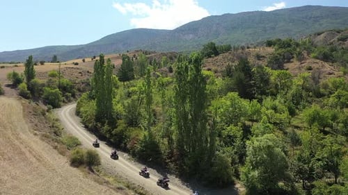 Aerial View Of Group Of People Riding On All Terrain Quadricycle Vehicle On Village Road