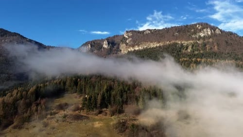 Aerial View of a Misty Mountainous Forested Landscape with a Rocky Cliff Shrouded