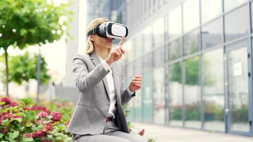 Businesswoman works using VR glasses in virtual reality simulator sitting on bench on street near