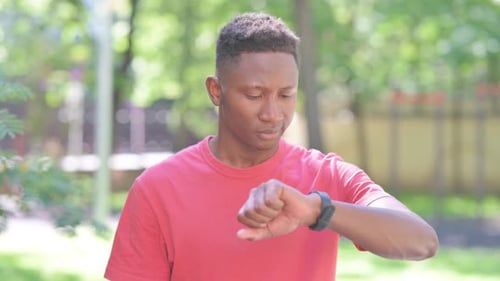Young Man Checks Watch, Looks to Side Outdoors