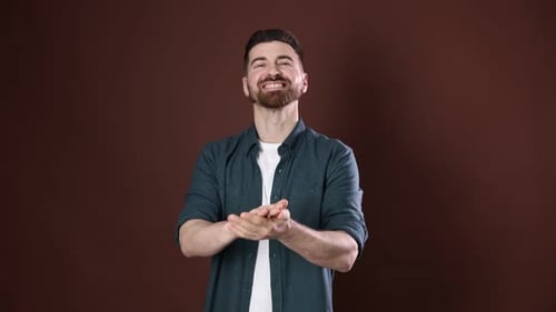 Positiver Mann klatscht in die Hände auf braunem Hintergrund