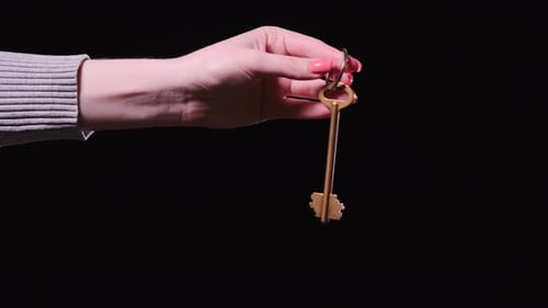 Woman's hand holds the key to a new apartment on a black background
