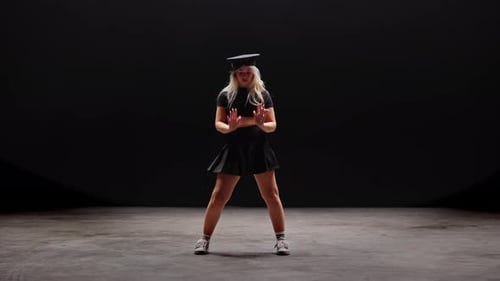 Junge Frau mit Polizistenhut tanzt im Studio vor schwarzem Hintergrund