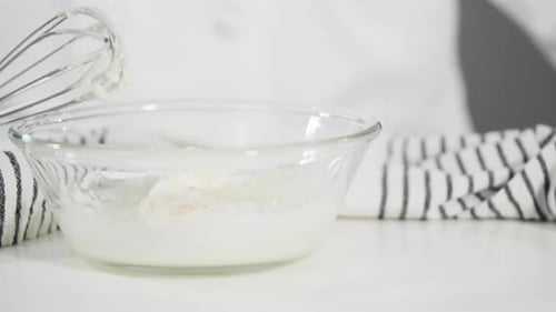 Zutaten in einer Glasschüssel mischen, um die Glasur für hausgemachte Zimtschnecken zuzubereiten