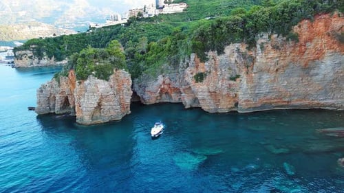 Motor Boat Floats in Sea Water Under High Cliffs