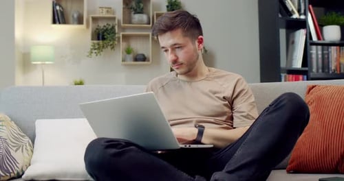 Man Working on Laptop Sitting on Couch Indoors