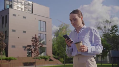 Businesswoman Browsing on Her Phone While Walking From Office