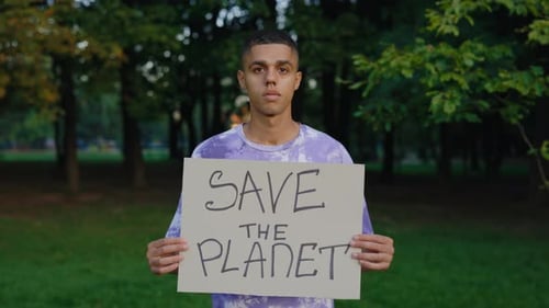 Young Man Holding Save the Planet Sign in Park