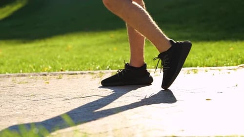 Caucasian Man Stretching Legs Before Outdoor Activities in Green Park on Sunny Summer Day Real Time