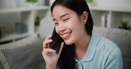 Happy Young Woman Talking on Smartphone Indoors