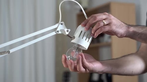 Homme remplaçant l'ancienne ampoule à filament par une nouvelle ampoule LED •UHD 4K