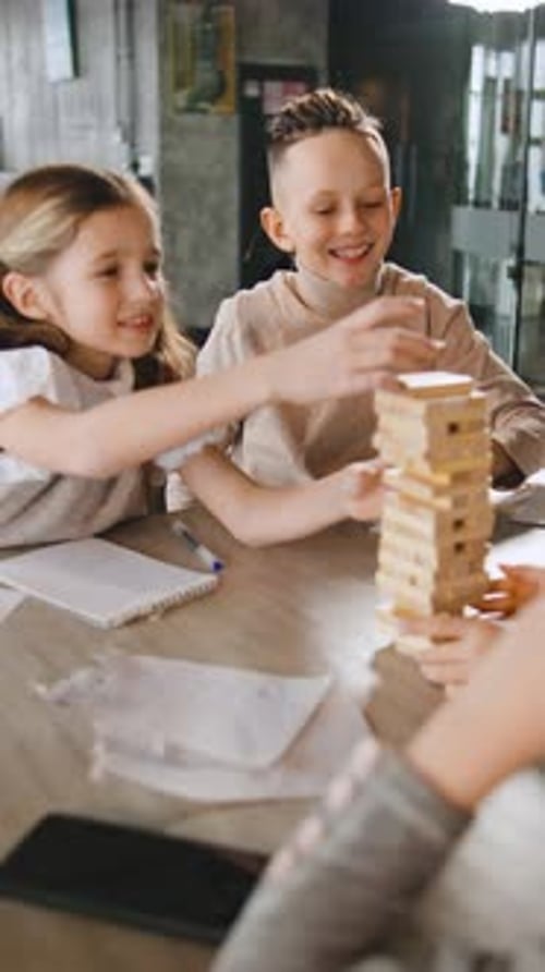Children Playing Wooden Block Stacking Game at Table