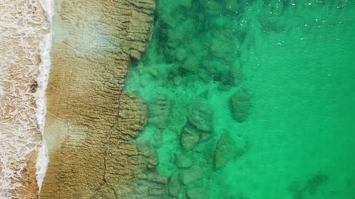 Rock formations under shallow turquoise sea water with soft calm waves, top view