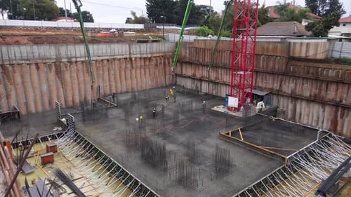 Aerial view of construction workers laying cement using automatic pump, Israel