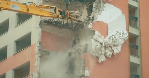 Demolishing a skyscraper with the help of construction equipment in a close-up view.