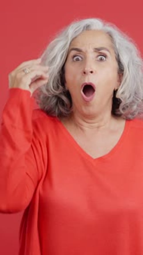 Senior Woman Gesturing with Hand on Red Background