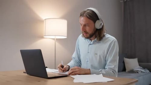Freelancer at Remote Work Man in Headphones in a Online Meeting on a Video Conference Workplace in