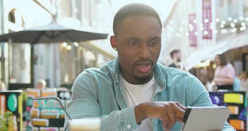 Attractive man in casual clothes using digital tablet checking datas from and financial reports