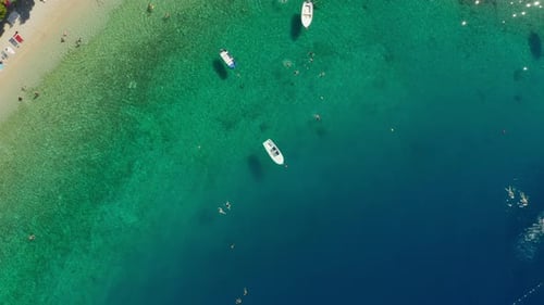 People swim in the sea and sunbathe on the beach at a resort in Croatia.