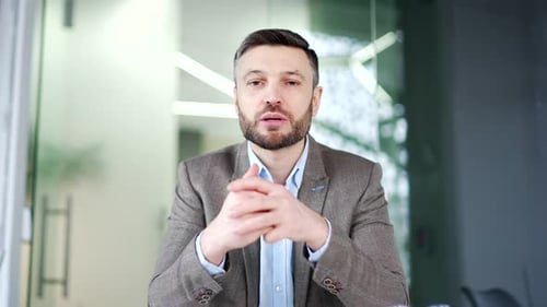 Webcam view. Confident businessman talking on a video call looking at camera sitting at workplace