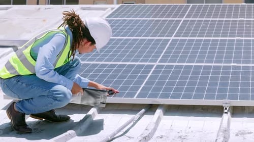 Technician Inspecting Solar Panels on a Rooftop