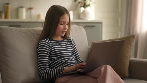Young Girl Using Laptop Computer on Sofa Indoors