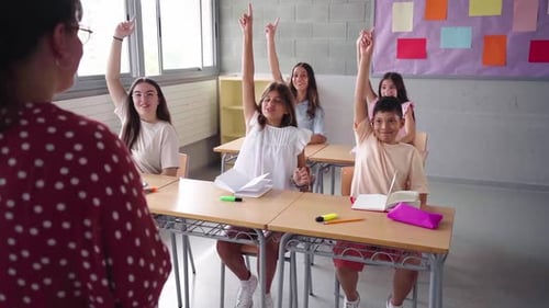 School Preteens at Classroom Raising Hands to Answer to the Female Teacher
