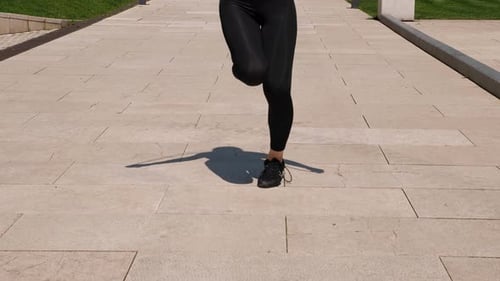 Closeup of a Sporty Woman Jumping Rope in a Modern City Park in Summer