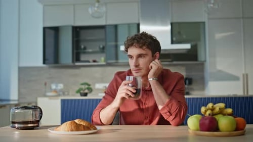 Young Adult Man Drinking Coffee at Breakfast Table