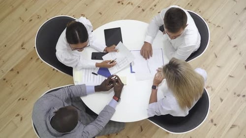 Multiethnic Group Discussing in a Meeting While Sitting at Round Table