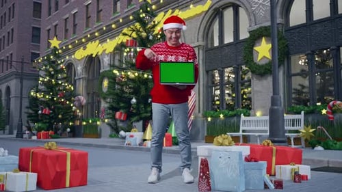 Asian Man In Christmas Suit With A Smile Pointing To Green Screen Laptop In Christmas Night