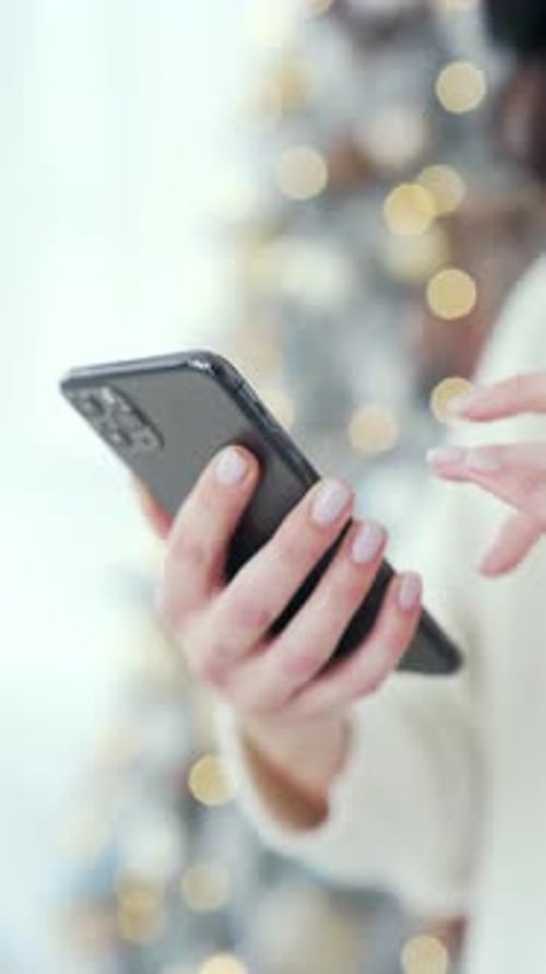 Woman hand hold smartphone at home or mall during winter New Year Xmas holidays. Female shopping