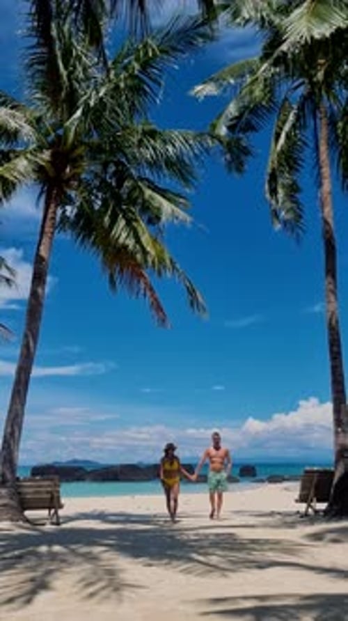 a Mature Couple Walking on a Tropical White Sandy Beach with Palm Trees in Thailand