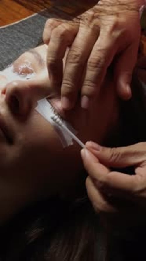 Aplicação de extensões de cílios no olho de uma mulher durante um procedimento de tratamento de beleza