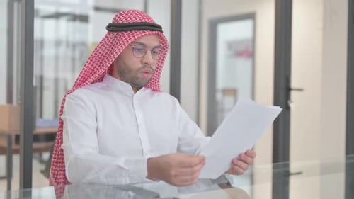 Young Arab Man Reading Documents at Work