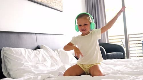 Happy Girl Dancing on Bed with Headphones