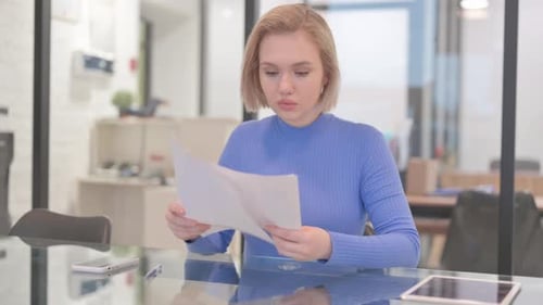 Woman Reviews Documents at Glass Table in Office