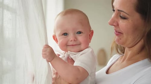Mother Holding Cute Baby Near Window, Kissing Head