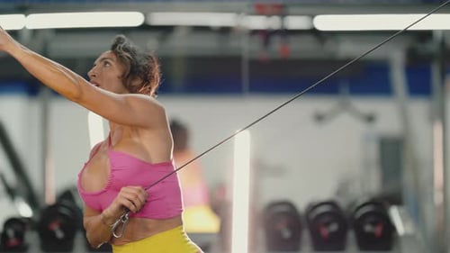 Determined Woman Performing Cable Crossover Exercise in a Gym