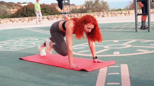 Redhead Woman Performing Mountain Climbers at Outdoor Gym