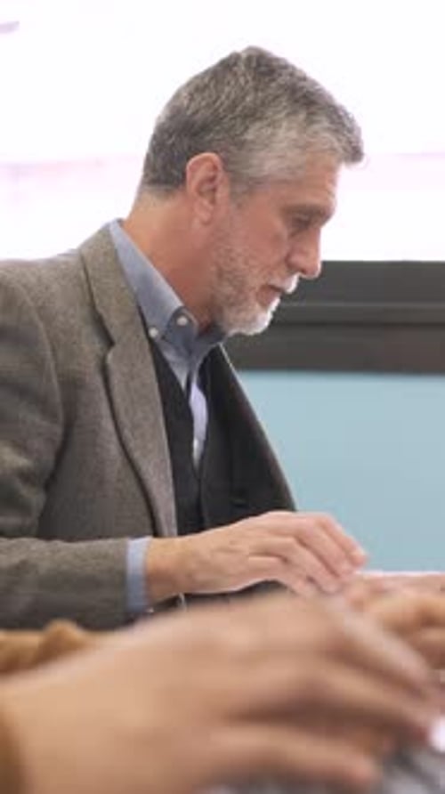Man Reviews Documents While Colleague Types