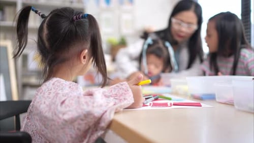 Teacher Helping Young Girl with Drawing in Classroom