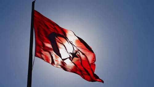 Red Flag Waving in Wind Against Blue Sky