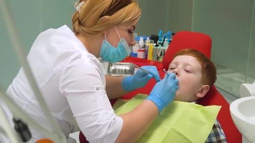 Closeup of Female Dentist Treating Little Boy in Dental Clinic