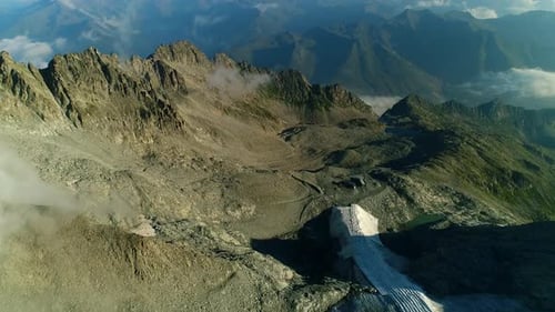 Aerial view over the alpine mountain chain. High view of the alps mountain peaks. Picturesque clouds