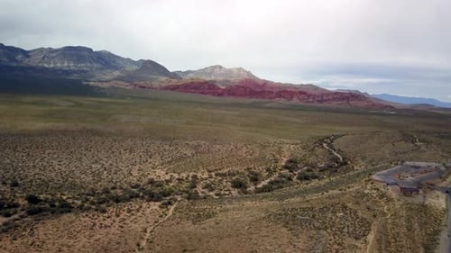 Aerial of Scenic Roadway in the foreground flying toward the red rocks of Red Rock Canyon in Nevada